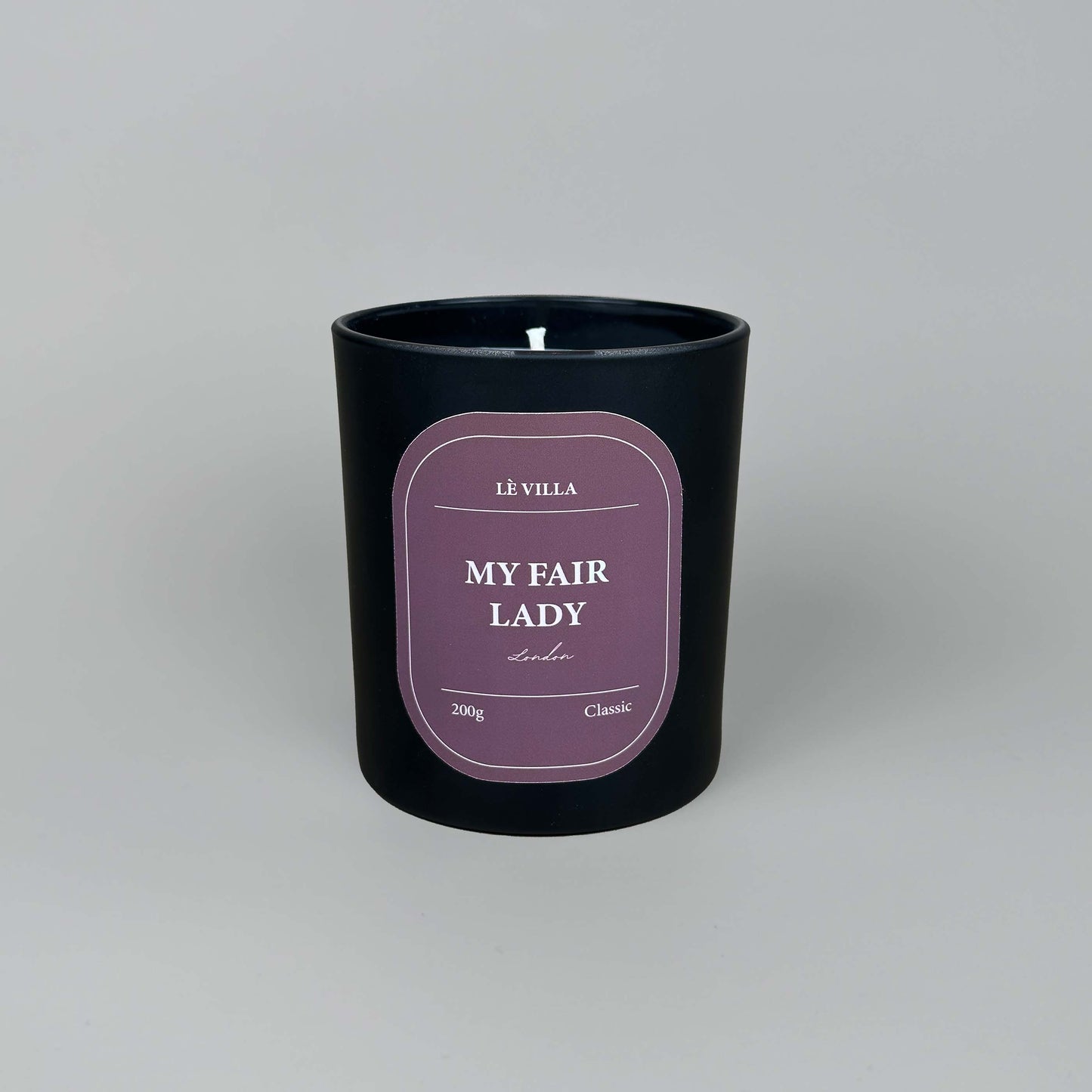 a matte black candle jar with a red label for london's my fair lady scent