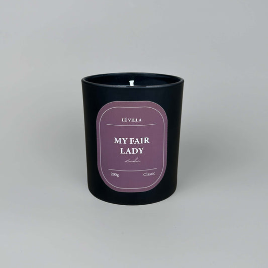 a matte black candle jar with a red label for london's my fair lady scent